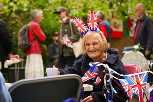 A woman wearing a headband with bunny ears made out of Union Jacks. She is holding a mug and smiling at the camera.
