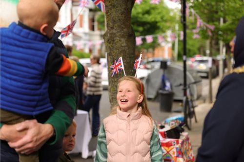 A young girl smiling and wearing a headband with Union Jack flags.