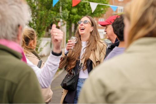 A woman laughing and holding a glass of wine.