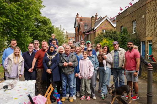 The Mayor of Wandsworth stands with a group of residents smiling and enjoying the celebrations at Alma Terrace, SW18.