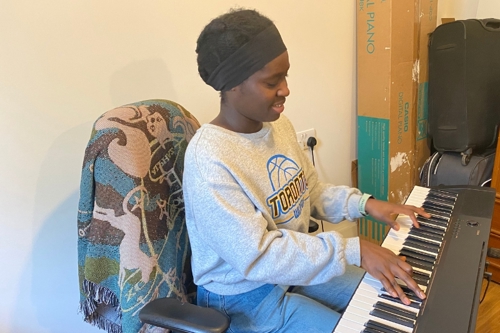 A young Black woman plays an electric keyboard
