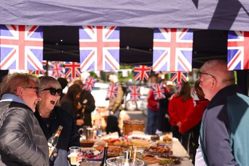 A group of people at a table with Union Jack bunting in the front of the shot.